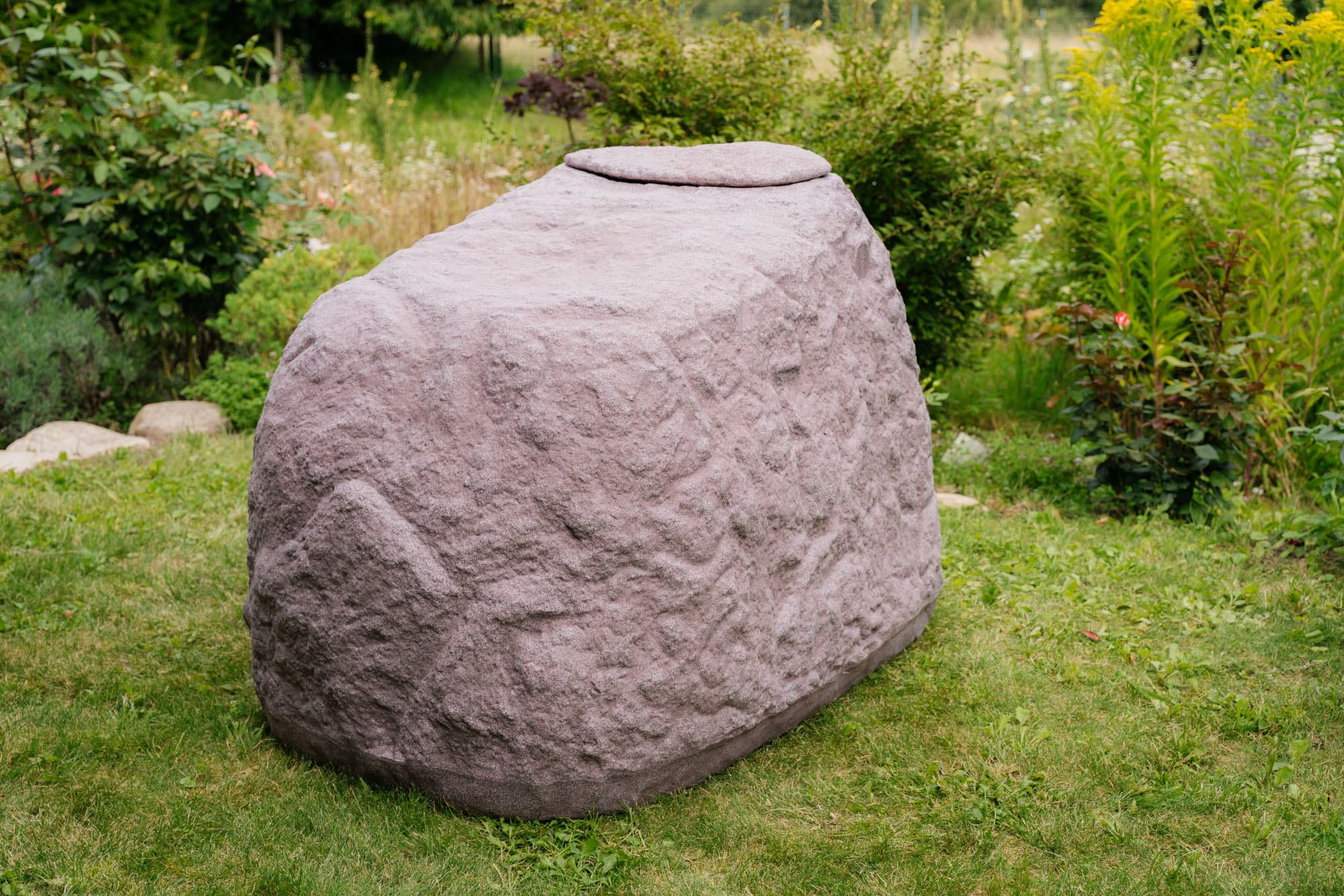 roter regenspeicher der im garten auf der wiese steht